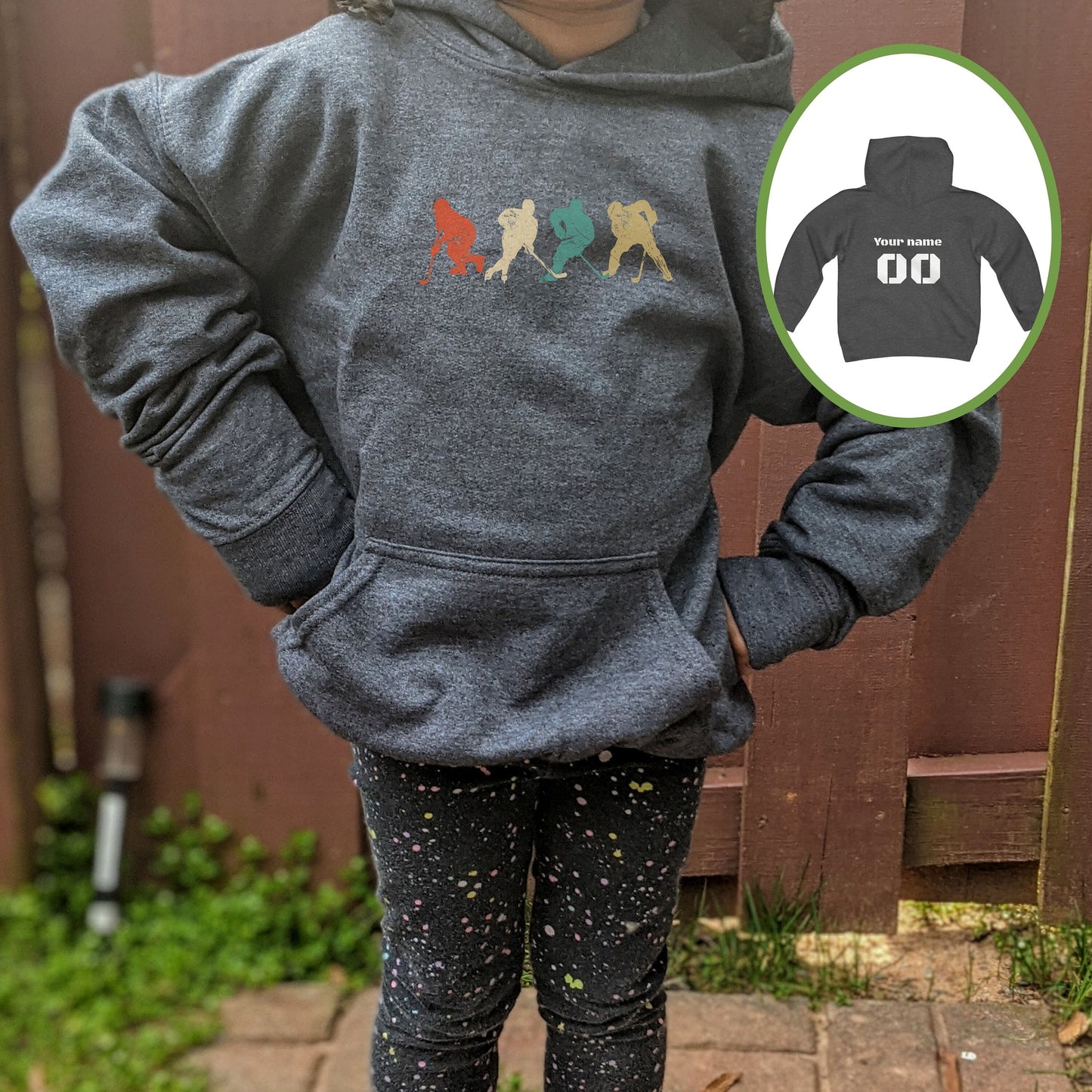 Girl wearing a dark heather Gildan 18500B youth hoodie. It has four figures of hockey players in a vintage distressed style. The colors are red, cream, blue and yellow. Personalized name and number available on the back.